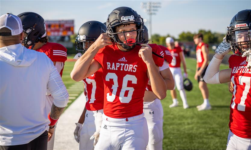 A football player puts on his helmet